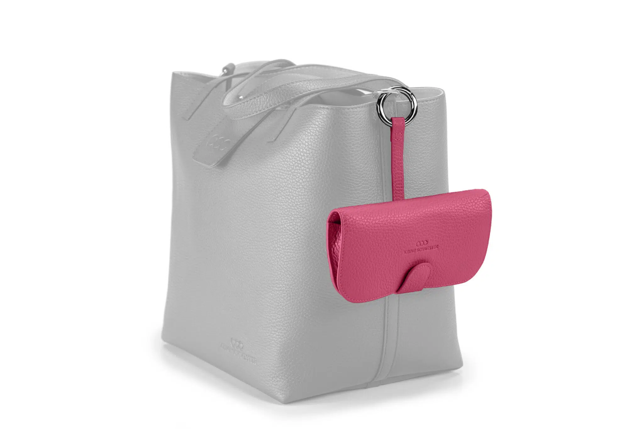 Premium Brillenetui aus genarbtem Leder in Pink mit silbernen Metallapplikationen, geschlossen, frontal fotografiert, hängend an einer Tasche